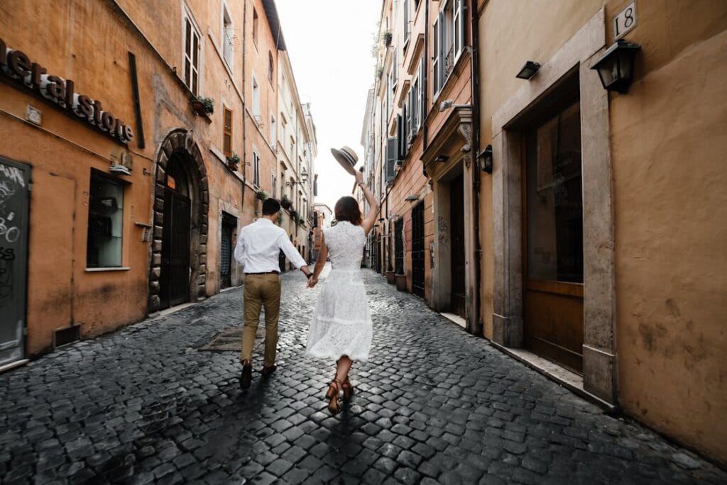 Couple walking hand in hand through cobblestone streets of trastevere
